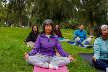 Multiracial women doing yoga meditation outdoor - Multi generational female group, mental health...