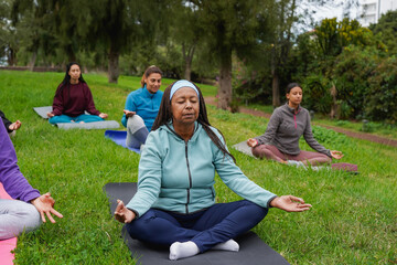 Multi generational african and latin women doing yoga meditation at city park - Diverse people,...
