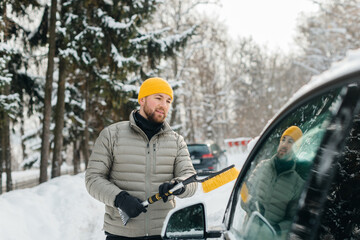 Driver clearing snow from electric car in winter