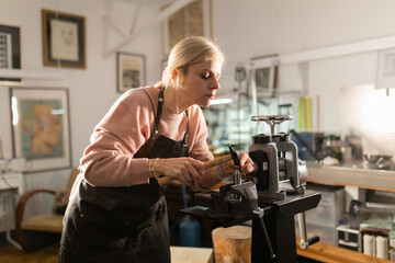 Woman metalsmith crafting jewelry in workshop using tools