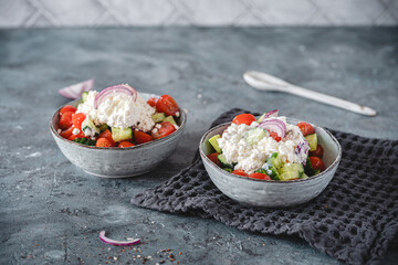 Two bowls of tomato cucumber salad with cottage cheese on gray background