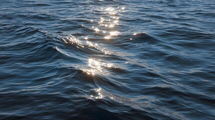 Naklejka premium Sunlight glints on the deep blue ocean waves creating a shimmering serene natural surface