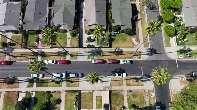 Aerial view of cars parked along 54th Street, amidst the residential houses and palm trees in Los Angeles, California, United States.