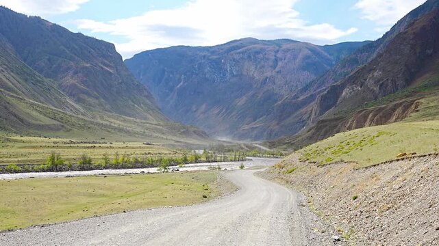 Gravel road running along Chulyshman river in mountain valley Altai Russia Remote travel route through scenic wilderness