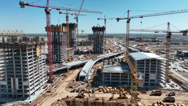 Sweeping aerial drone shot gliding smoothly over a massive construction zone featuring numerous cranes and infrastructure development below growth, architecture, structure