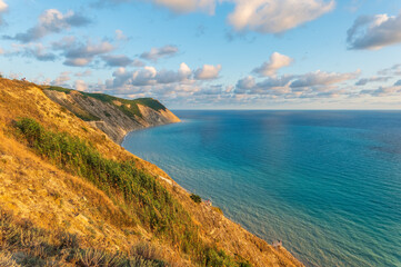 Obraz premium High mountain slopes to the Black Sea coast in Anapa, Russia. Coastline in sunset, beautiful sea scenery. Anapa coast landscape, high cliff