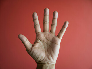 Closeup of a hand with palm facing forward on red background
