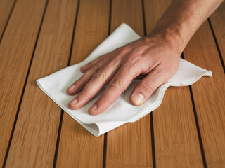 Hand wiping down a wooden surface with a white cloth