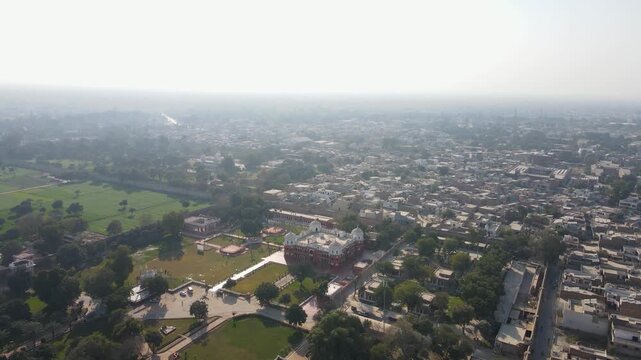 Aerial view of the Noor Mahal palace with its red brick facade surrounded by lush green gardens and pathways, Bahawalpur, Punjab, Pakistan.