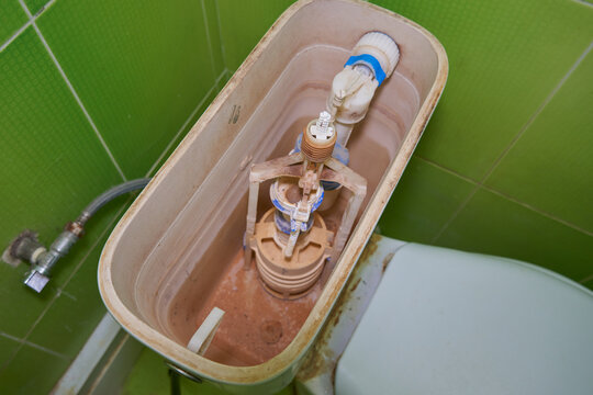 old dirty internal mechanism of a toilet flush tank, broken Toilet flushing mechanism brown plaque and traces of rust, toilet maintenance