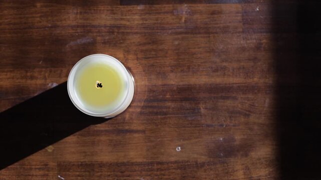 Straight down flat lay of burning candle in white jar on wood table