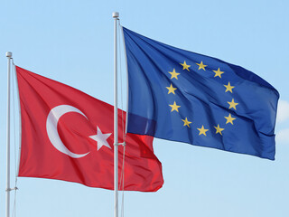 Turkish and European flags waving side by side under clear blue sky