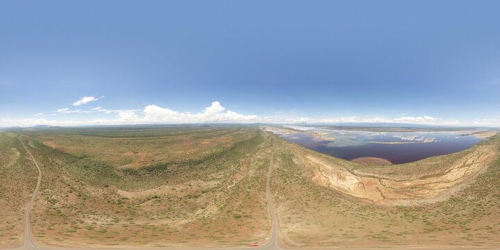 Aerial view of a vast, sun-soaked landscape with a striking contrast between the arid earth and the blue sky, Magadi, Kajiado County, Kenya.