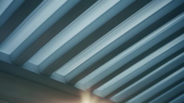 Intense sun creating a radiant lens flare as it shines through the gaps of a bioclimatic pergola or automated louver roof, providing shade and outdoor comfort