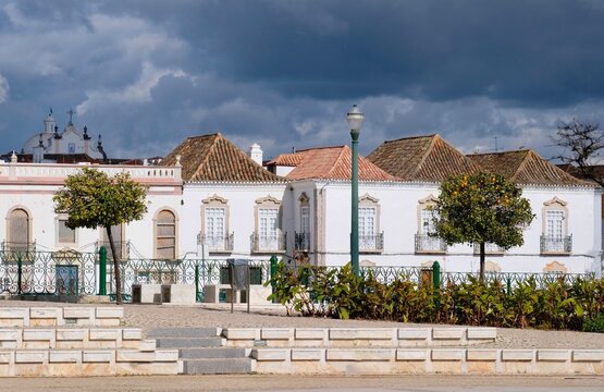 The whitewashed houses on the Gil&atilde;o River in Tavira against a backdrop of dark rain clouds.Tavira, Algarve, Portugal