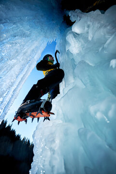 Man climbing frozen ice wall at winter mountains