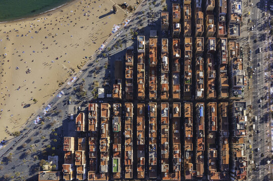 Aerial view of La Barceloneta terracotta rooftops baking under the sun, contrasting with the pale sands and turquoise sea, Barcelona, Catalonia, Spain