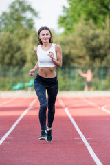 Fototapeta premium Young Caucasian Woman Jogging Outdoors on a Track During Sunny Weather