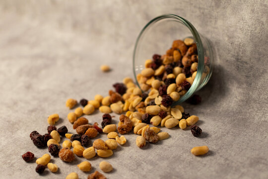 Trail mix spilling out of a glass bowl. 