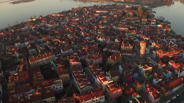 Aerial view of the vibrant, colorful houses of Burano, casting shadows in the golden light, creating a striking contrast against the water, Venice, Veneto, Italy.