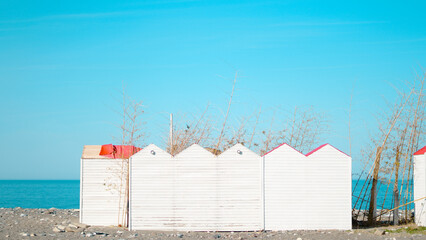 Beach huts with colorful roofs along rocky shoreline by the sea