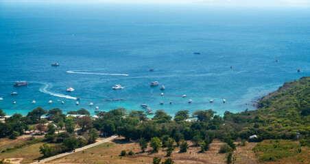 Naklejka premium Aerial view of the blue sea and sky over a scenic coastline with a green bay and summer activity beach on the horizon landscape .