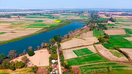 An aerial view shows a patchwork of fertile farmland near a river, with neatly divided plots of...