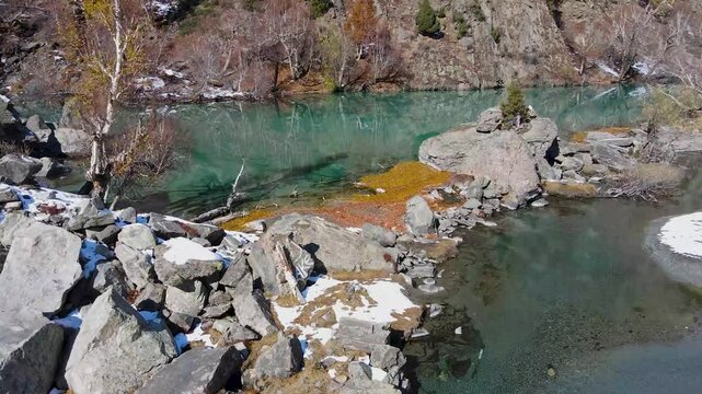 Aerial view of the pristine Naltar Lake showcasing the mesmerizing turquoise waters contrasted against the rugged terrain, Hunza, Gilgit, Pakistan.