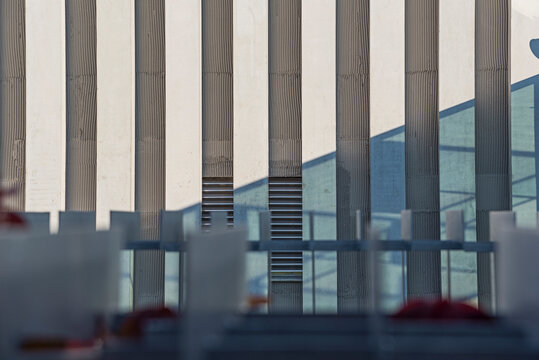 Modern facade with vertical grooves, geometric shadows and blue accents in bright sunlight