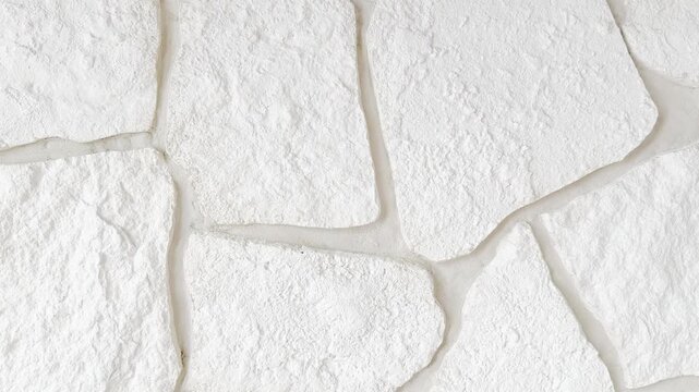 White decorative stone wall texture in close-up. Natural stone surface with detailed relief, clean neutral color, and modern architectural style. Ideal background for construction, renovation, interio