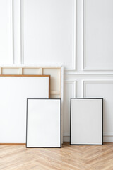 An Assortment Of Unadorned Photo Frames Leaning On Traditional White Decorative Molding On Wooden Flooring