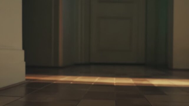 Warm sunlight creating diagonal patterns on a classic tiled floor in an empty room, emphasizing cozy domestic atmosphere and inviting glow entering interior space