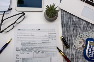 Top view of tax preparation desk with calculator laptop US dollars and 1040 tax documents