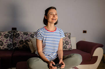 Happy young woman holding a video game controller in a cozy home environment. Gaming lifestyle,...