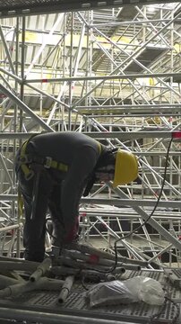 Construction worker with yellow hard hat working on scaffolding.