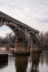Fototapeta premium Weathered Concrete Arch Bridge Over River with Ornate Railing