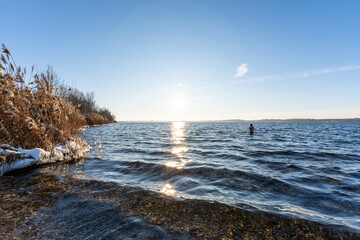 Eine Frau geht im Winter im Cospudener See baden
