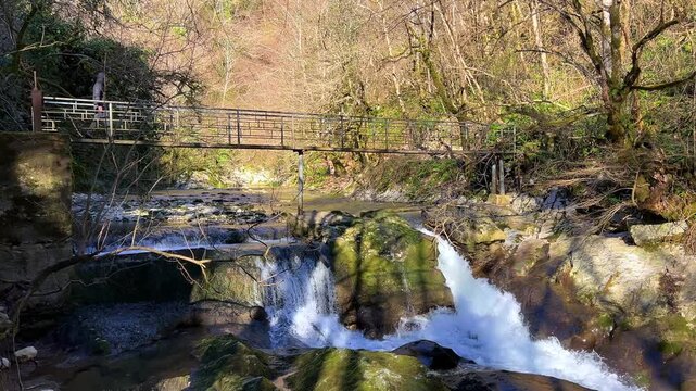 Waterfall in the picturesque Chernigov Gorge in the Caucasus Mountains. A man walks through the Chernigov Gorge Mountain Park with the Malaya Machara River, Abkhazia. Chernigovka. 4К