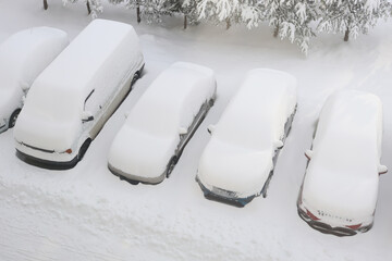 Snow-covered cars in winter parking lot
