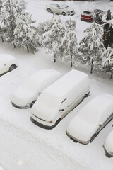 Snow-covered cars in winter parking lot amid heavy snowfall