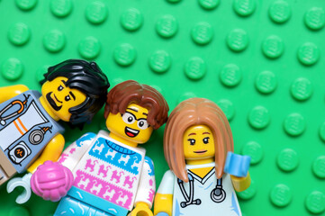 Naklejka premium Three Lego minifigures: Veterinarian, medical worker and cat lover on a green background, close-up.