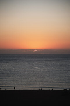 Golden sunset over the ocean with silhouettes of people on the beach at twilight.