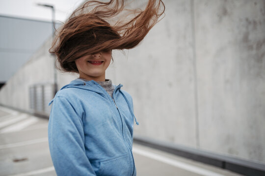Outdoor portrait of young girl with long hair standing on playground in the city.