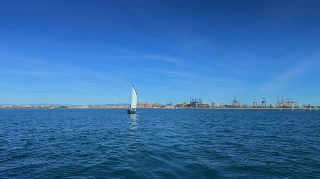 Valencia sailboat sailing on Mediterranean Sea with sun reflections
