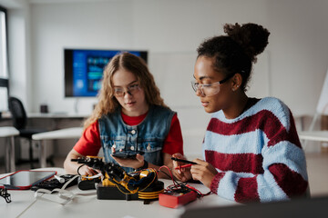 High school students working on robotics project, using online AI app to answer questions. © Halfpoint