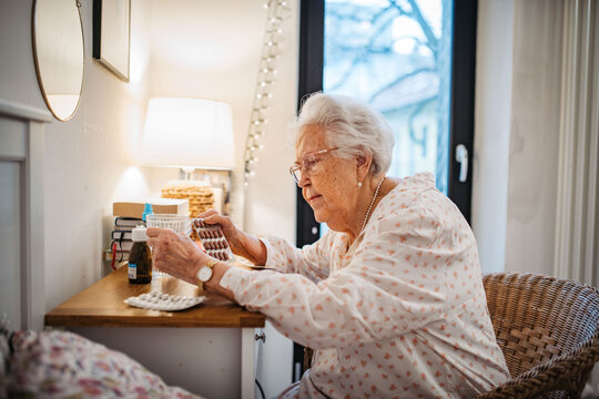 Senior woman taking prescribed pills after waking up.