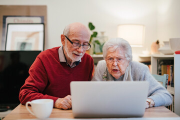 Fototapeta premium Loving elderly couple exploring digital world together, using laptop.