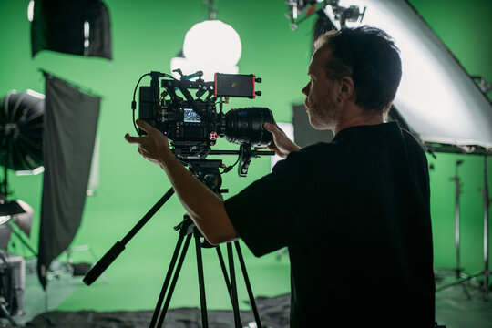 Director of photography with a camera in his hands on the set. Professional videographer at work on filming a movie, commercial or TV series. Filming process indoors, studio