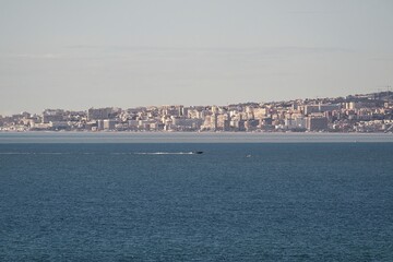 Speedboat moving across the Mediterranean Sea with Malaga city skyline in the background on a calm cloudy day
