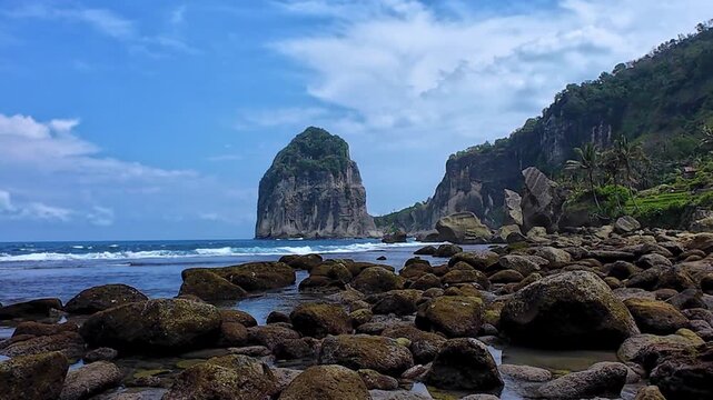 Pangasan Beach with high cliffs, Pasitan. Indian Ocean. View of a black sand beach and coral reef in East Java, Indonesia. Waves on the beach behind the picturesque cliffs. 4К